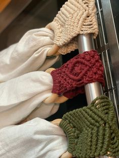 four knitted mittens hanging on a metal rack with white gloves attached to them