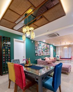 a dining room table with colorful chairs and pictures on the wall in the backround