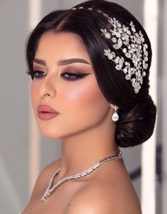 a woman wearing a bridal headpiece with flowers on it's side and pearls in her hair