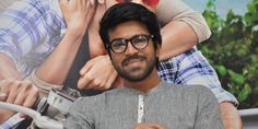 a man with glasses standing in front of a movie poster