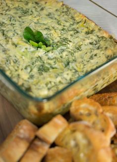 a casserole dish with spinach and cheese in it next to crackers