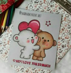 there is a card with two teddy bears hugging each other on the table next to colored crayons