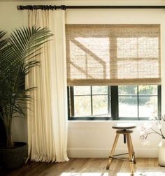 a living room with wooden floors and large windows covered in natural shades of bamboo blinds