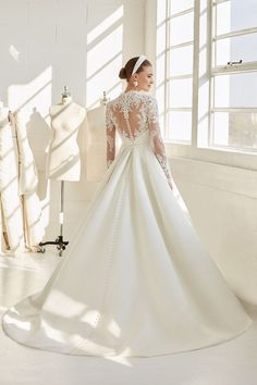 a woman in a white wedding dress standing next to a mannequin