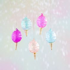 three ornaments hanging from strings with snow flakes on the top one is pink, blue and green