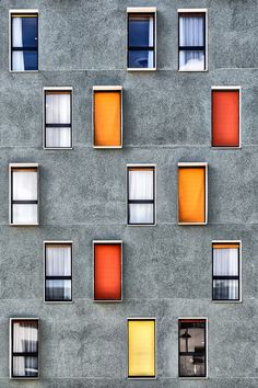 several windows are shown on the side of an apartment building with multiple colors in them