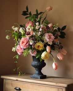 a vase filled with lots of flowers sitting on top of a dresser