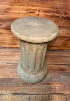 an old stone pedestal sitting on top of a wooden floor