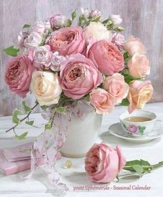 a vase filled with lots of pink flowers next to a cup and saucer on a table