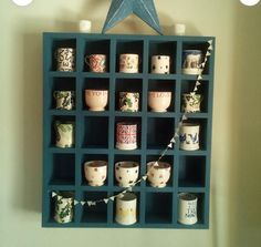 a blue shelf with cups on it and a star hanging from the wall