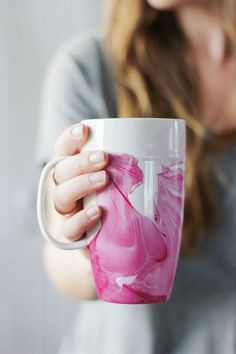 a woman is holding a coffee mug with pink swirls on the outside and inside