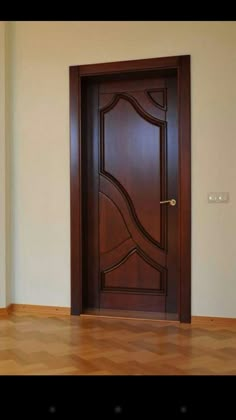 an empty room with a wooden door in the center and hard wood flooring on the other side