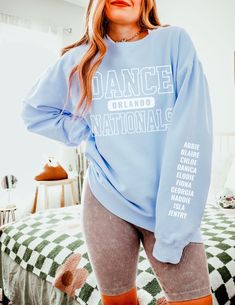 "Custom City Dance Nationals Crewneck, Personalized Names Sleeve Dance Gear, Retro Competitive Dancer Gift, Unisex Comfort Colors Sweatshirt How To Order - Please make sure you have looked at all sizes and color charts. - Select from the various T-shirt sizes and colors from scroll-down menus. - Fill in the personalization box (if provided) as exemplified. - Click \"Add to cart\" button. You can turn back and add more items of different size and color. Order Process - Our processing time is 5-10 days. - Standard Shipping, 2-5 business days (after processing time). Product This custom crewneck sweatshirt brings both incredible quality and amazing style to the mix. Made with soft, ring-spun cotton fabric with 100% cotton threads, it sits unmatched when it comes to softness. All sweatshirts f Stretch Graphic Print Tops For Dance Class, Stretch Letter Print Tops For Dance, Stretch Tops With Graphic Print For Dance Class, Stretch Long Sleeve Tops For Dance, Relaxed Fit Crew Neck Top For Dance, Long Sleeve Graphic Print Tops For Dance, Graphic Print Long Sleeve Tops For Dance, White Crew Neck Top For Dance Class, Stretch Long Sleeve Tops For Dance Class