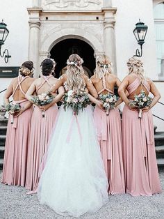 a group of bridesmaids standing in front of a building with their backs to the camera