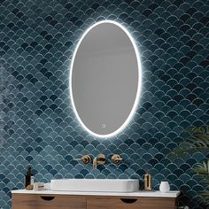 a bathroom vanity with a round mirror above it and blue tiles on the wall behind it