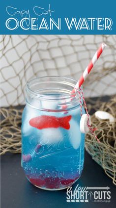 a glass jar filled with blue liquid next to a red and white striped straw