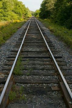 an old railroad track with trees in the background