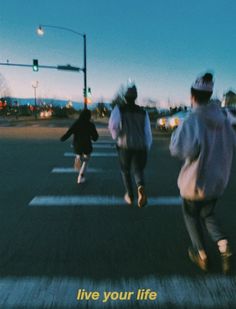 three people walking across a cross walk at an intersection with the words live your life written on it