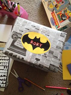 a batman themed box sitting on top of a floor next to other toys and supplies