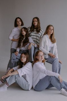 a group of young women sitting next to each other on the floor in front of a white background