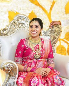 a woman sitting on top of a white chair wearing a pink dress and gold jewelry