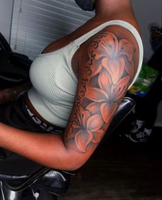 a woman sitting on a motorcycle with a flower tattoo on her arm and shoulder,