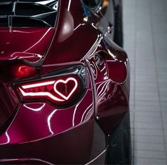 the rear end of a red sports car with a heart on it's tail light