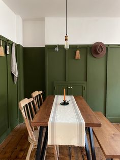 a dining room with green walls and wooden floors, including a table set for four