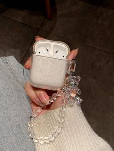 a woman holding an apple airpods case in her hand with a chain attached to it