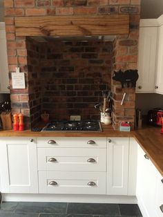 a kitchen with white cabinets and a brick wall behind the stove top, along with wooden counter tops