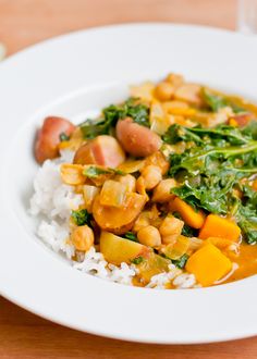 a white plate topped with rice, beans and greens on top of a wooden table