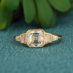 an antique diamond ring with three baguettes on it and green leaves in the background