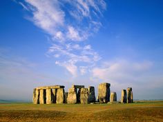 the stonehenge monument stands in an open field under a blue sky with wispy clouds