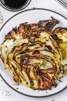 grilled cabbage on a white plate next to a glass of wine and some condiments