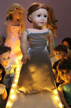 a group of dolls standing next to each other in front of a table with lights on it