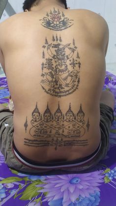 the back of a person's body with tattoos on it and an image of buddhas