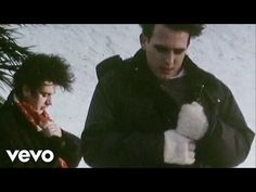 two men standing next to each other in front of snow covered ground with one holding a teddy bear