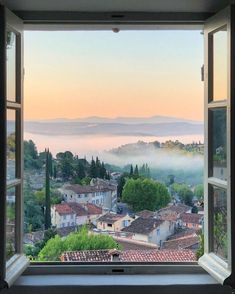 an open window with the view of a town in the distance and fog coming from behind it