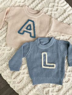 two sweaters with the letter l on them are laying next to eachother