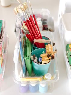 there are many different items in the container on the table, including pens and pencils