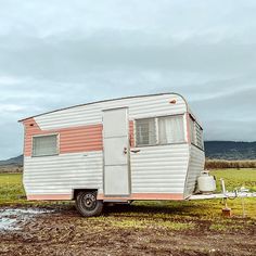 an old trailer is parked in the middle of a field