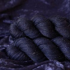 several skeins of black yarn sitting on top of a purple velvet material sheet