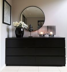 a black dresser with two candles and a mirror