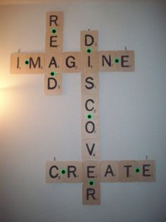 a cross made out of scrabble tiles with words on the wall above it