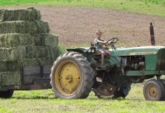 a man riding on the back of a green tractor