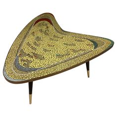 an artistically designed tray with gold and green designs on the top, sitting on a wooden stand