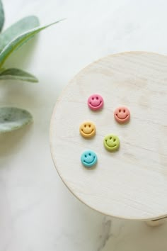 four different colored buttons sitting on top of a white table next to a plant and potted leaf