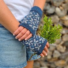 a woman holding a plant in her left hand while wearing knitted fingerless gloves