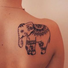 an elephant tattoo on the back of a woman's shoulder