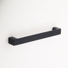 a black shelf mounted to the side of a white wall with a handle on it